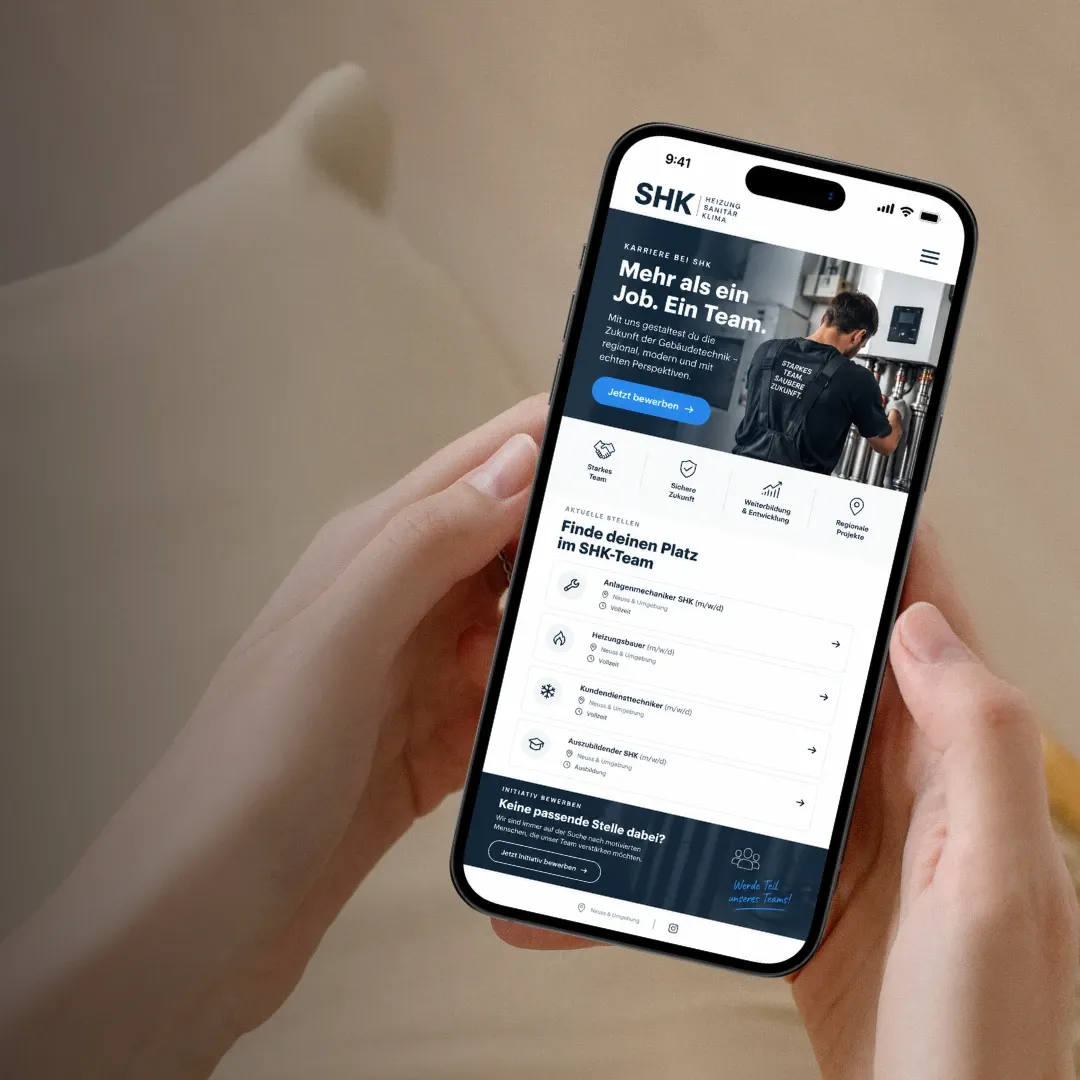 Zwei Hände halten ein Handy mit der Karriereseite eines SHK-Betriebs und offenen Stellen für Anlagenmechaniker und Heizungsbauer