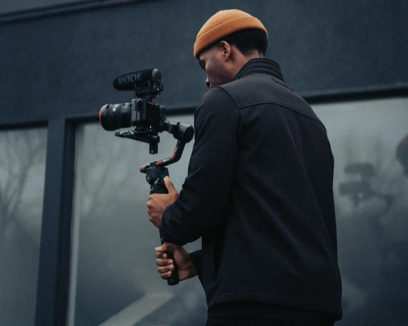 Kameramann mit Kamera und Gimbal beim Videodreh vor einem Gebäude